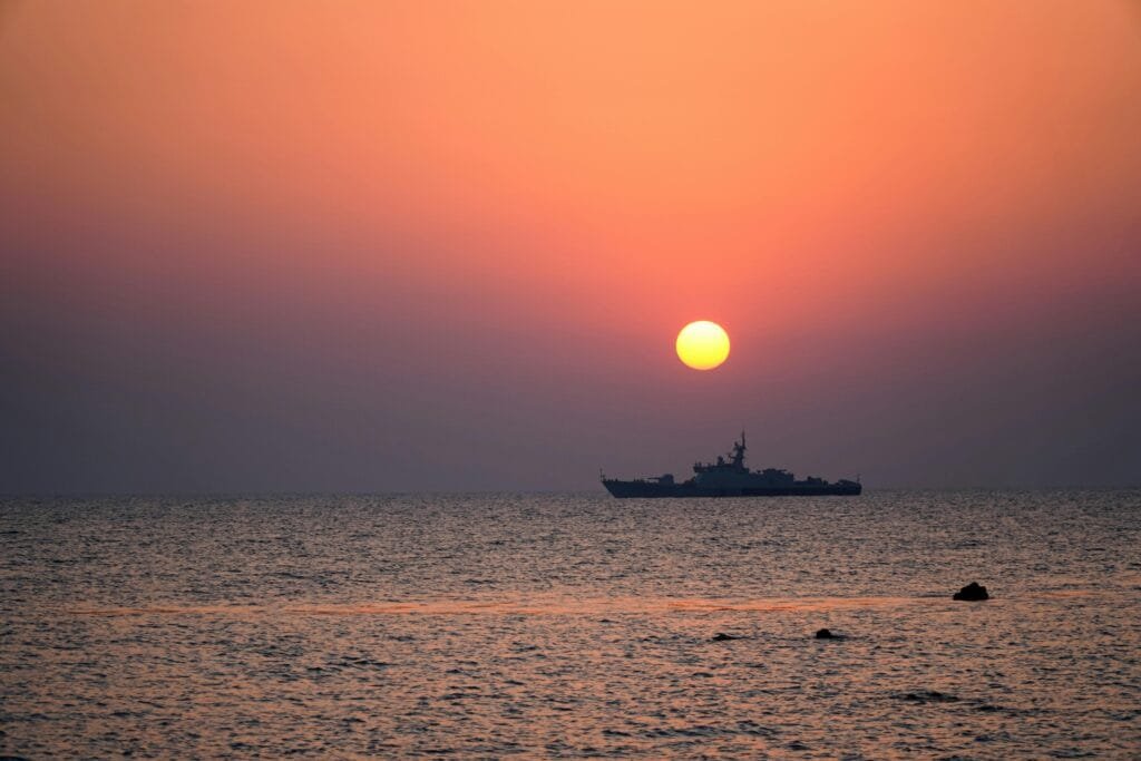 A serene sunset over the ocean with a ship silhouette, perfect for travel inspiration.