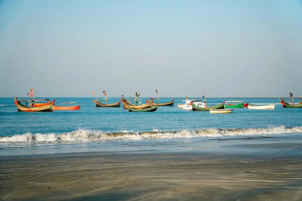 Colorful fishing boats float on calm blue waters near a peaceful tropical beach.